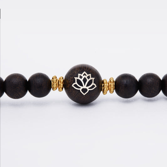 Élément central en bois d’agar incrusté d’or avec motif de fleur stylisée.