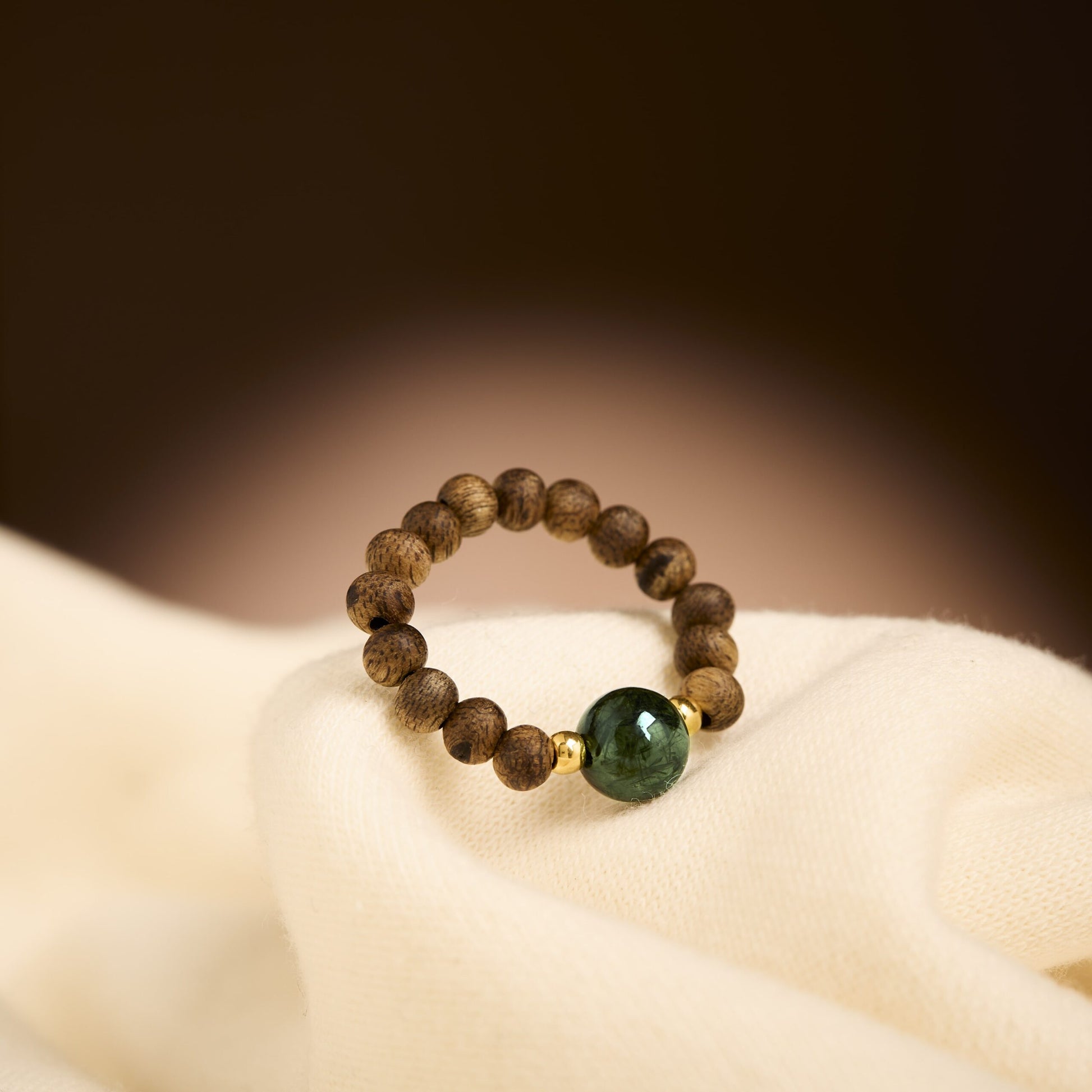 Bague composée de perles en bois d’agar formant un cercle harmonieux autour d’une pierre centrale.