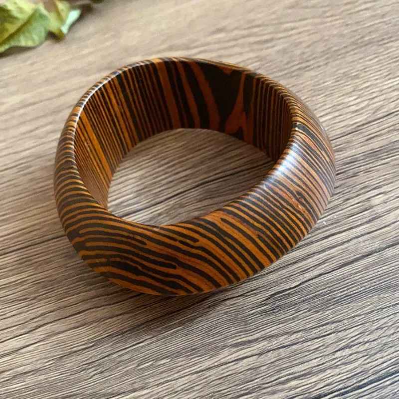 Accumulation de bracelets manchettes en bois naturel, mêlant formes pleines et veinages contrastés avec harmonie.