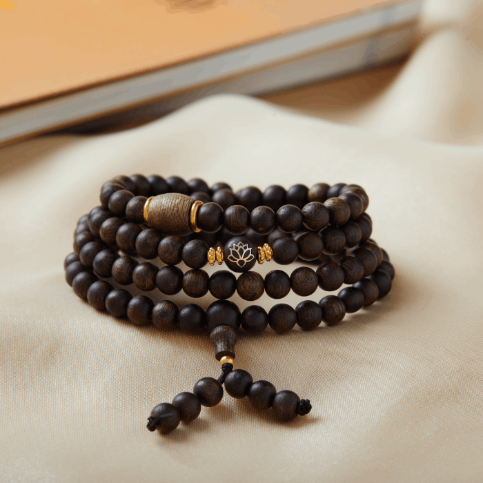 Bracelet en bois d’agar composé de 108 perles assemblées en multi-tours avec cordon ajustable.