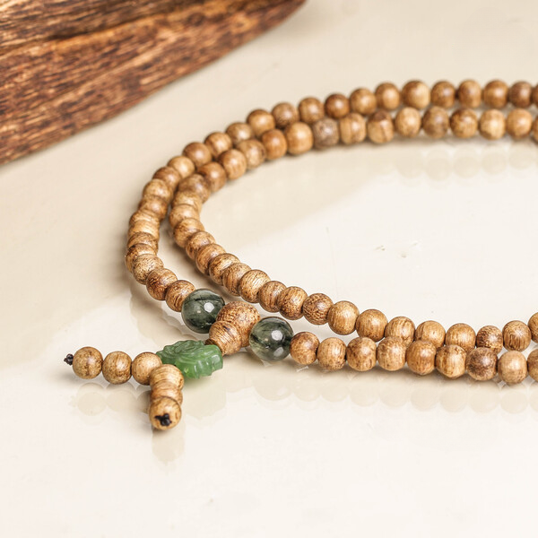 Bracelet bouddhiste de type mala avec 108 perles en bois d’agar. Le montage sur cordon conserve un style sobre.