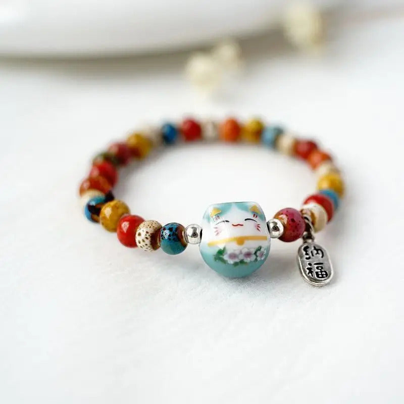 Bracelet de chance avec chat porte-bonheur, perles décoratives et breloque argentée pour un bijou chargé de sens.