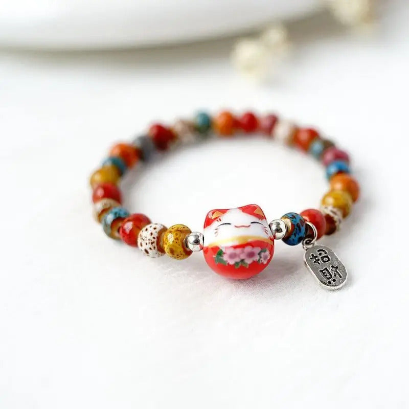 Le chat décoré de détails floraux apporte une touche tendre au bracelet, entouré de perles colorées et d’une breloque argentée.