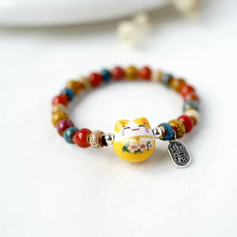 Les perles aux nuances vives mettent en valeur le chat porte-bonheur japonais et donnent au bracelet une présence joyeuse.