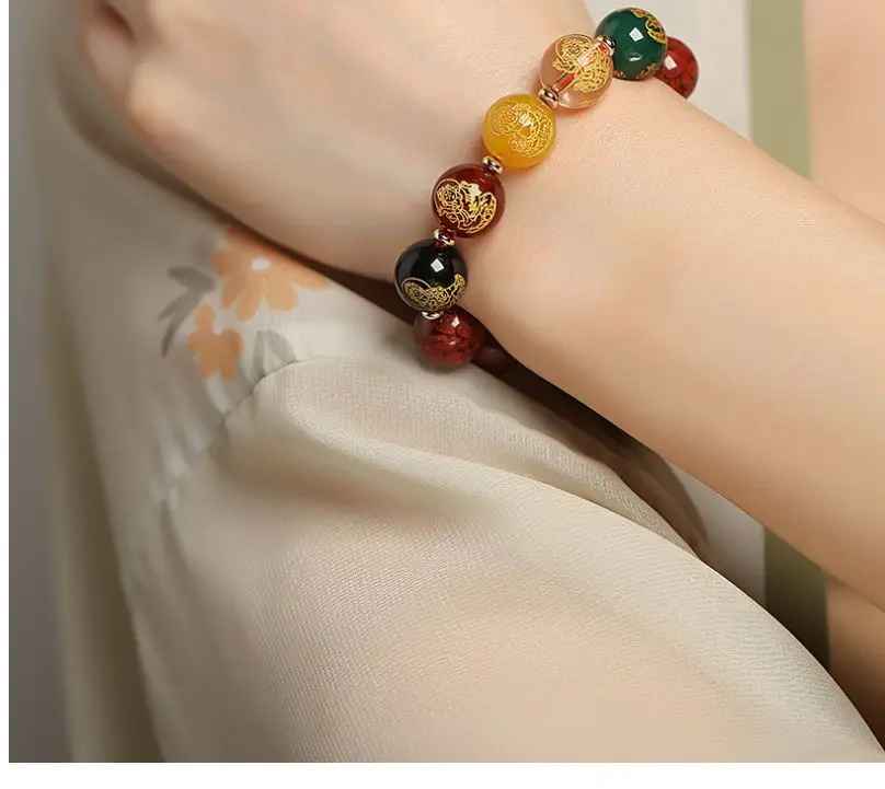 Gros plan sur les perles rouges en cinabre reconstitué et les motifs dorés finement gravés.