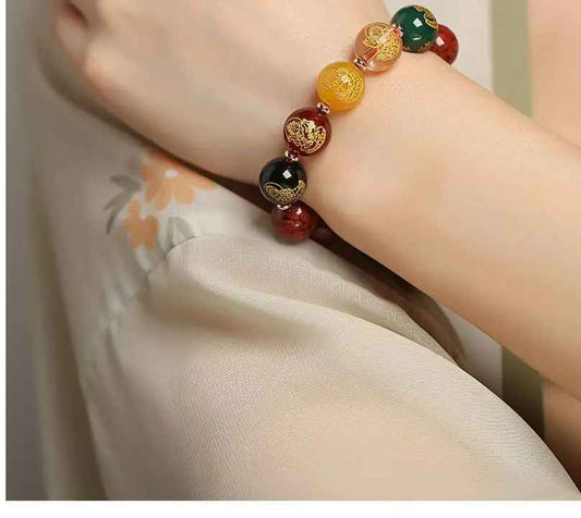 Gros plan sur les perles rouges en cinabre reconstitué et les motifs dorés finement gravés.