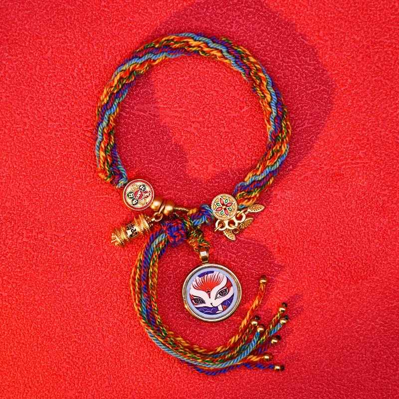 Bracelet tressé avec plusieurs symboles protecteurs en métal doré.