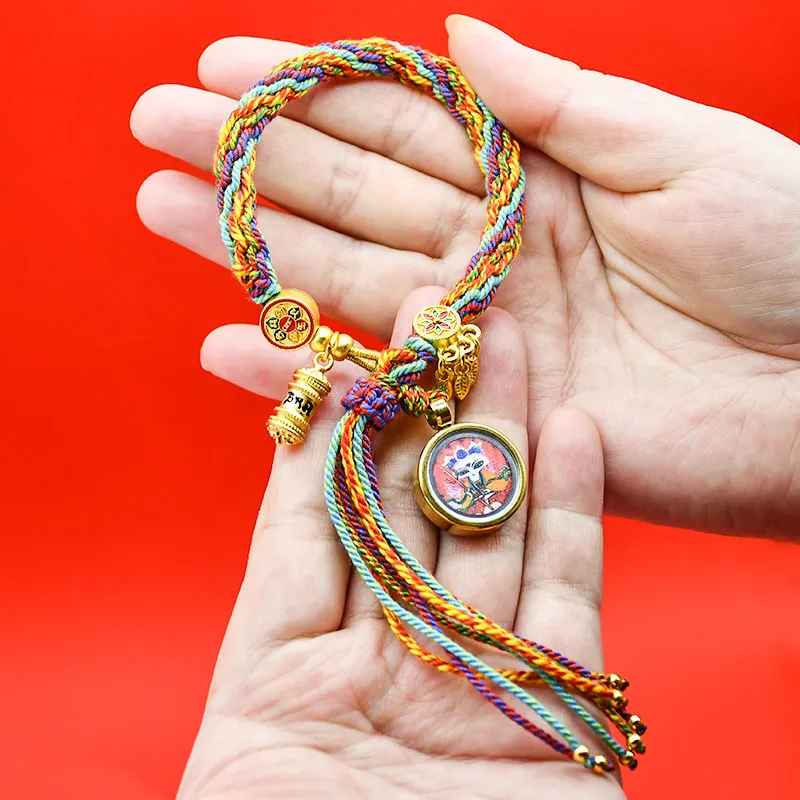 Bracelet artisanal en coton tissé, couleurs vives et symbole spirituel doré.