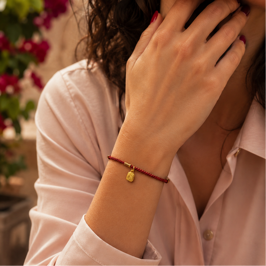 Bracelet cordon rouge Feng Shui avec breloque dorée gravée. Son style fin apporte une touche symbolique et discrète au poignet.