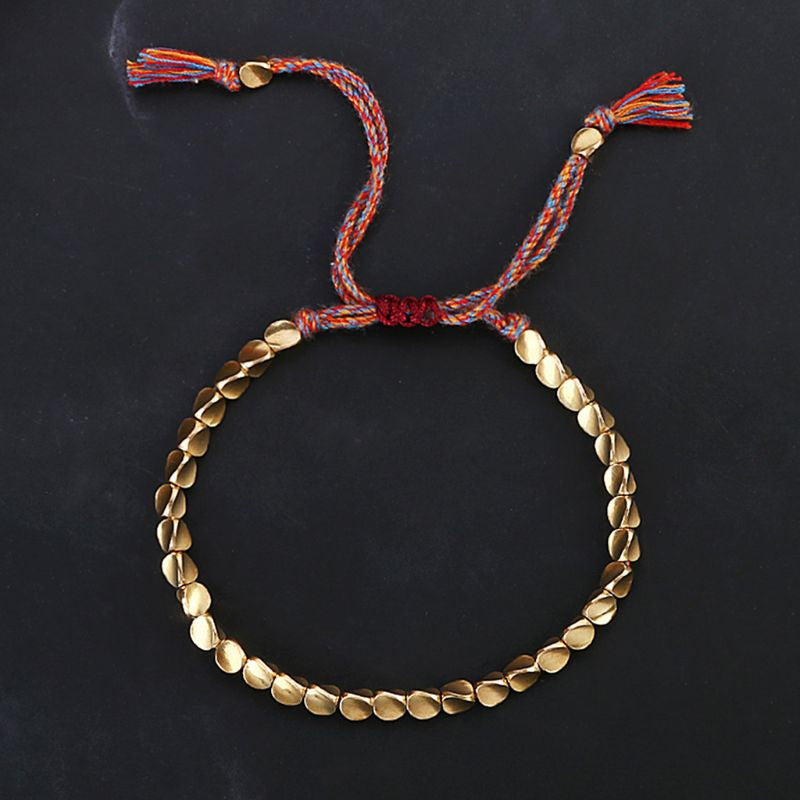 Bracelet artisanal en perles rondes dorées avec tressage macramé rouge et multicolore.