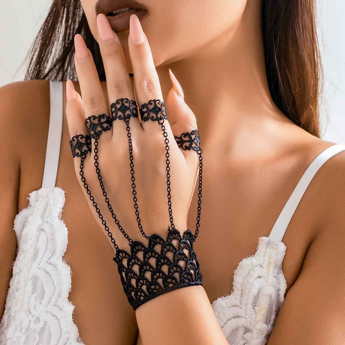 Bracelet en dentelle noire avec chaînes fines reliées aux doigts.