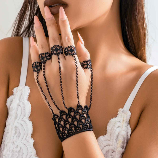 Bracelet en dentelle noire avec chaînes fines reliées aux doigts.