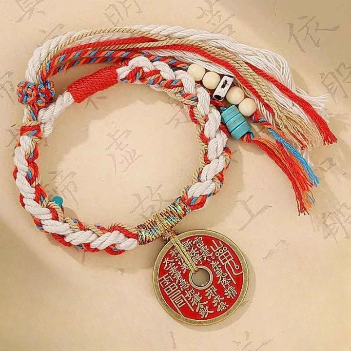 Bracelet Feng Shui tressé avec amulette protectrice rouge et or en main.