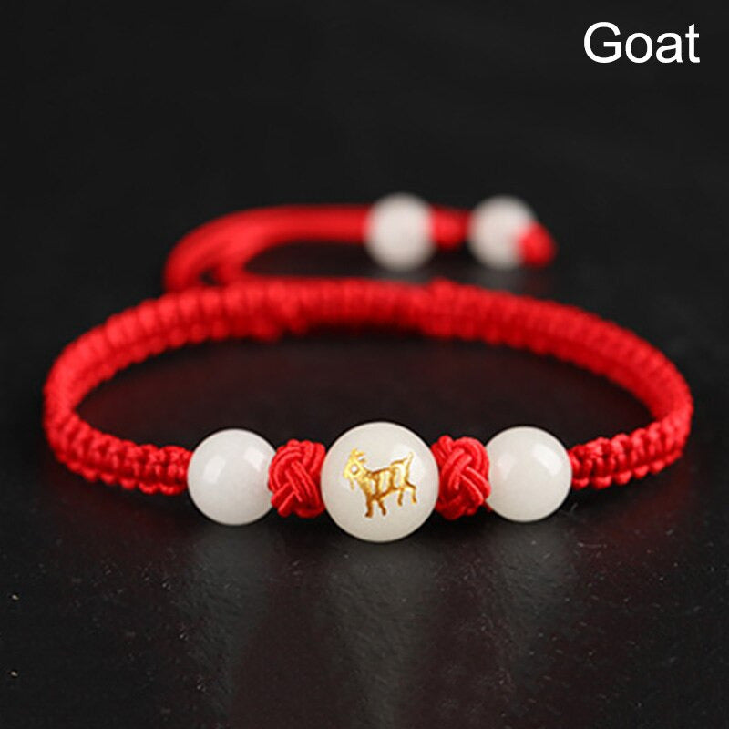 Bracelet rouge Feng Shui avec médaillon du signe de la Chèvre, tressage lumineux et détail zodiacal protecteur.