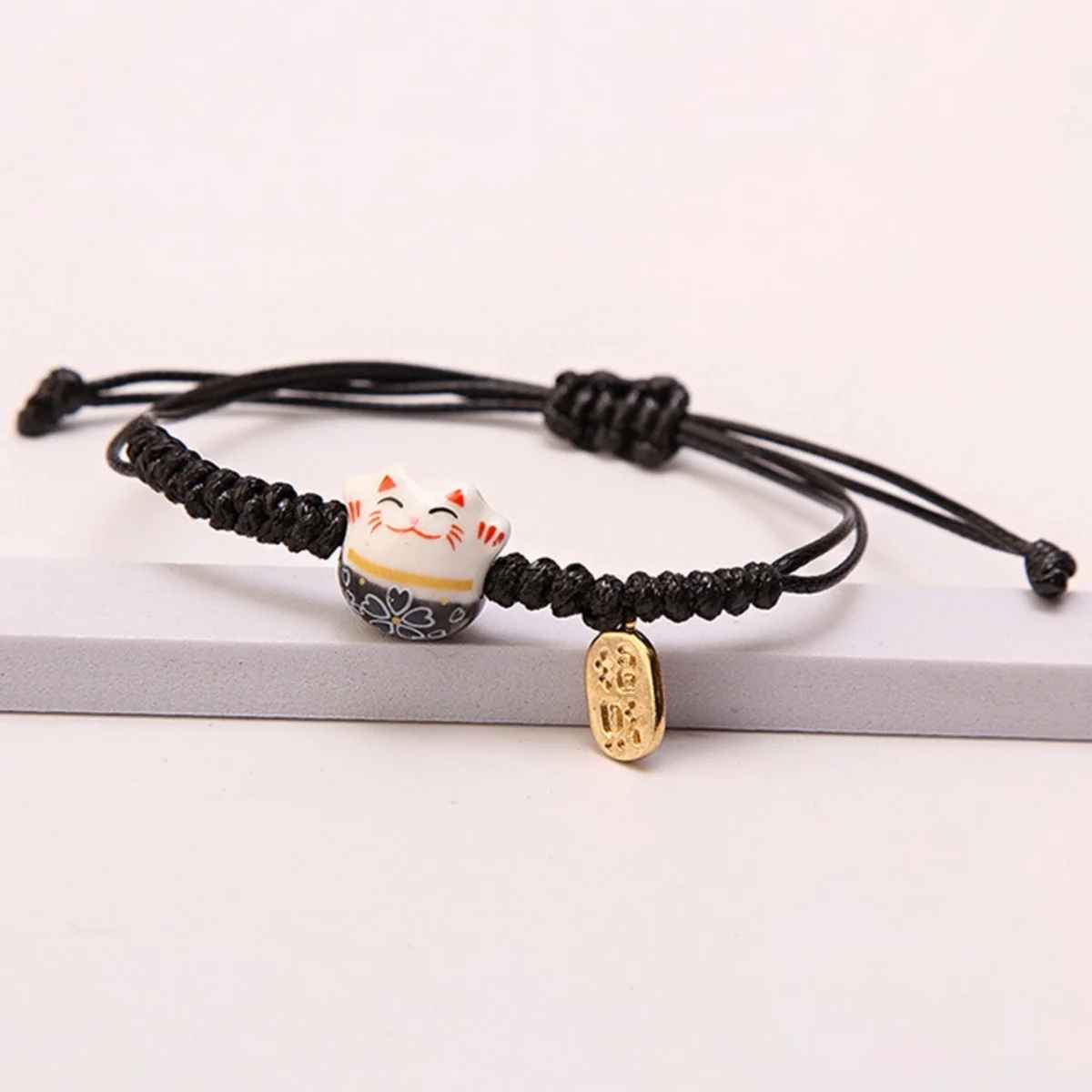 Bracelet fait main Feng Shui, fil rouge et figurine de chat chanceux en céramique noire.