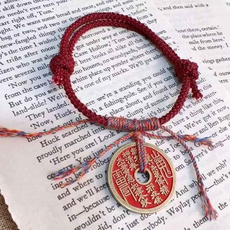 Bracelet tressé blanc et rouge avec amulette porte-bonheur.