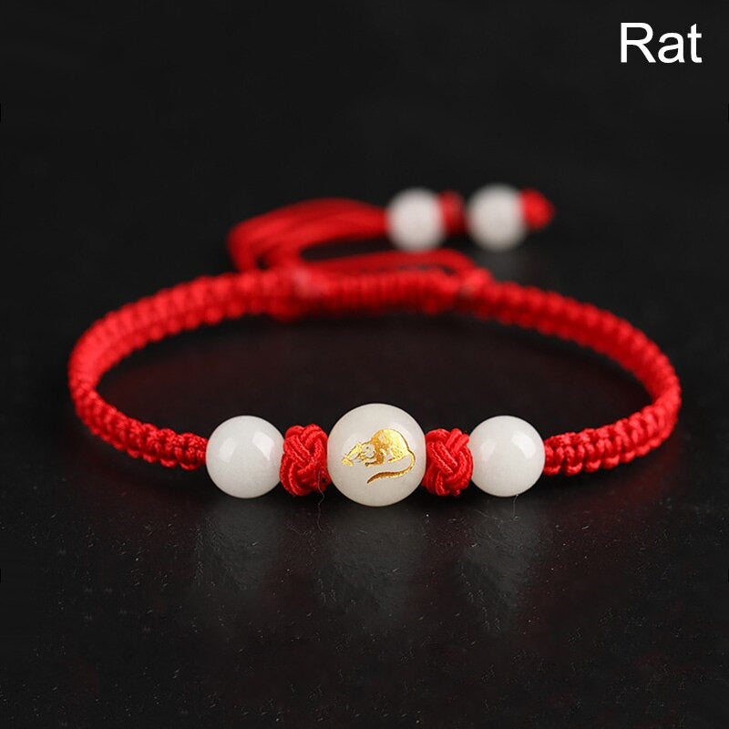 Vue rapprochée du médaillon du bracelet zodiaque chinois lumineux sur fond rouge. Signe du rat ou signe de la souris.