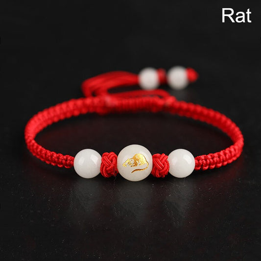 Vue rapprochée du médaillon du bracelet zodiaque chinois lumineux sur fond rouge. Signe du rat ou signe de la souris.