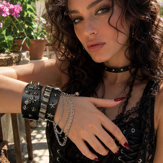 Une jeune femme porte nos bracelets gothiques empilés avec une manchette ornée de détails métalliques et de chaînes, pour une allure audacieuse et raffinée. Cette composition met en valeur un bijou de caractère pensé pour sublimer un style affirmé.