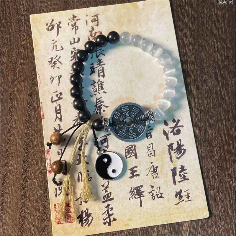 Gros plan sur le pendentif Taiji Yin Yang noir et blanc suspendu sous le bracelet.