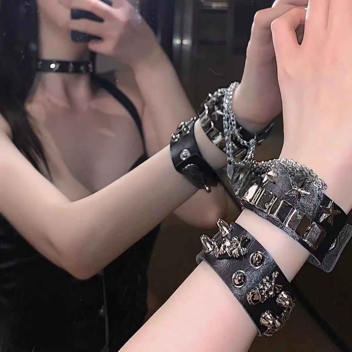 Vue rapprochée des têtes de mort chromées sur bracelet punk en cuir noir.