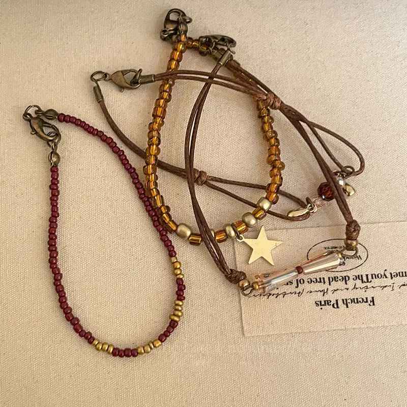 Association de bracelets boho en perles dorées, bordeaux et cristal ambré.