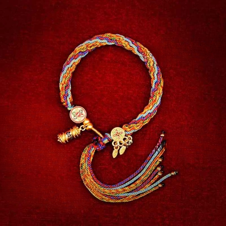 Bracelet tressé en coton multicolore avec breloque dorée inspirée du bouddhisme.