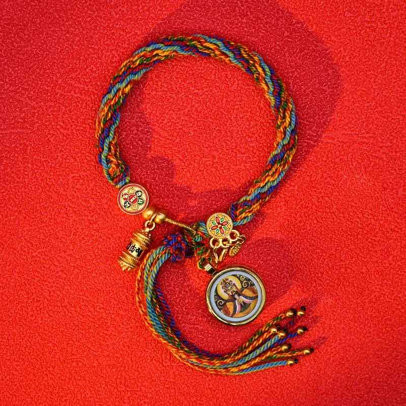 Bracelet coloré avec petite roue de prière dorée suspendue au centre.