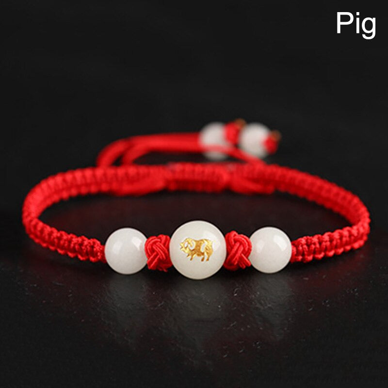 Bracelet porte-bonheur rouge orné du signe du Cochon, symbole de générosité, abondance et prospérité chaleureuse.
