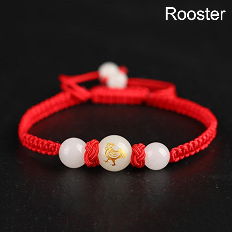 Bracelet rouge tressé avec un médaillon fluorescent représentant un coq, signe astrologique chinois.