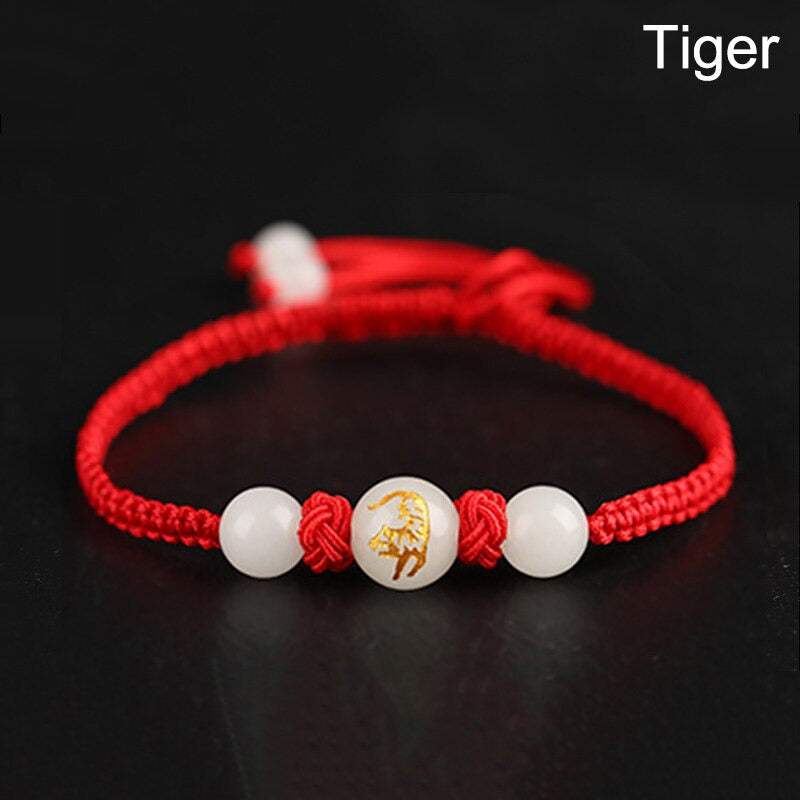 Bracelet rouge Feng Shui avec médaillon du Tigre, symbole d’audace et de protection active.