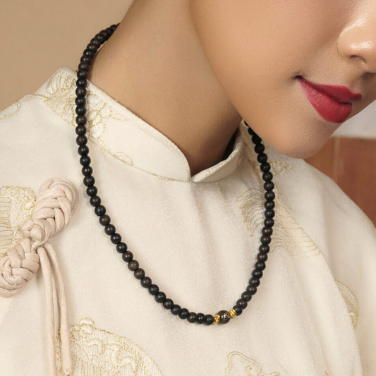 Collier en bois d’agar présenté dans un écrin rigide, soulignant la sobriété et l’équilibre du bijou.