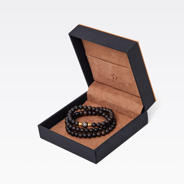 Collier en bois d’agar porté autour du cou dans une tenue sobre et élégante.