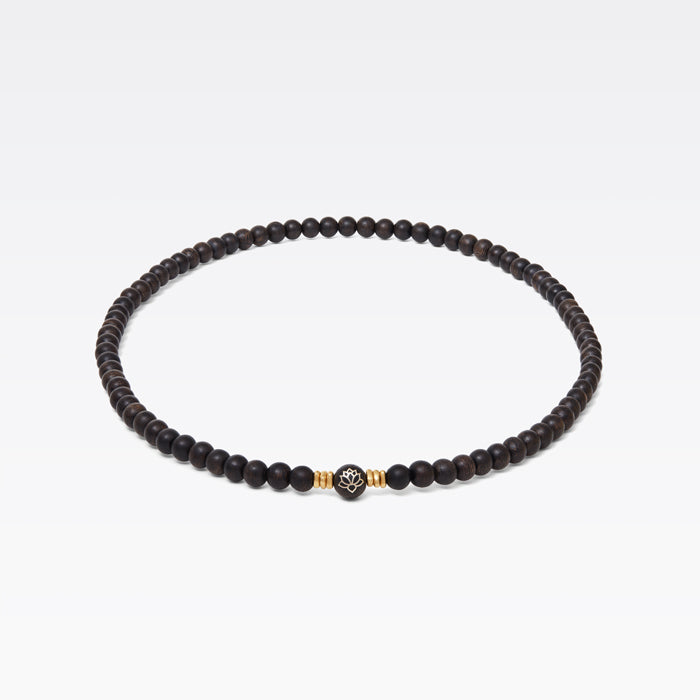 Motif lotus incrusté d’or 14 carats sur perle centrale en bois d’agar.