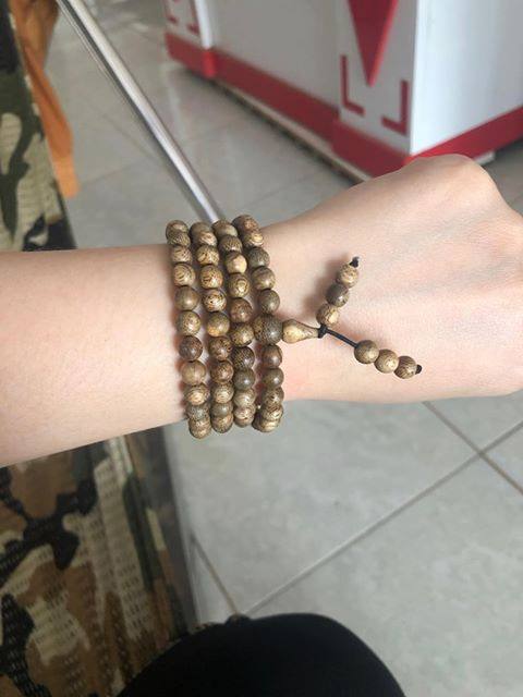Détail des perles en bois d’agar naturel alignées sur un bracelet de 108 perles.